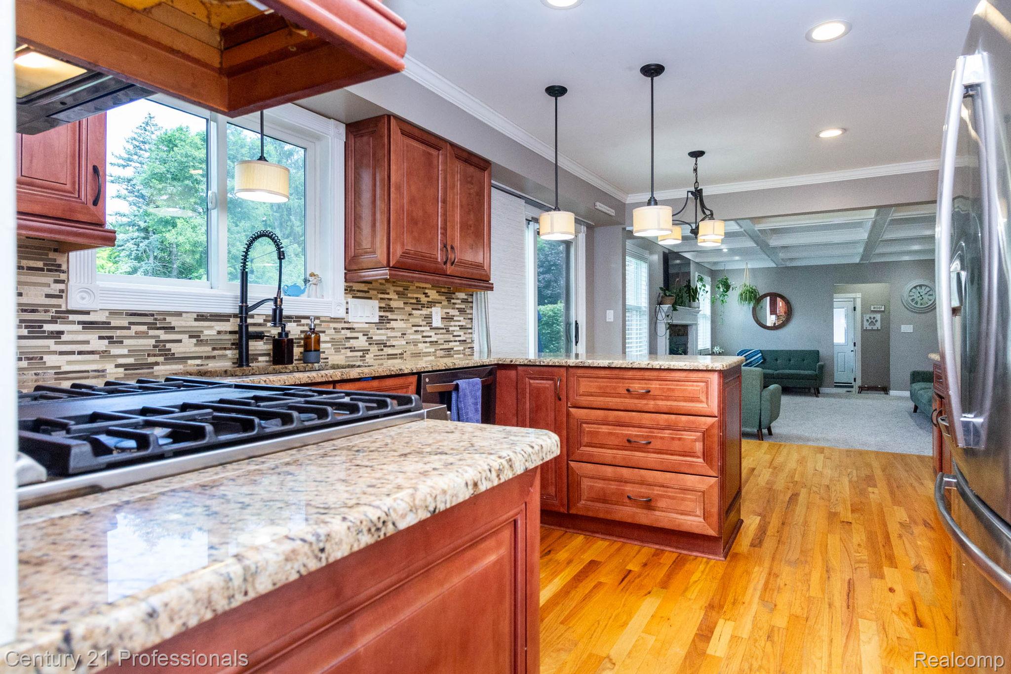 671 Bridgestone Drive Rochester, MI 48309 - Photo 10 of 50 Kitchen featuring granite countertops, wood-finish flooring, a mosaic tile backsplash, a built-in gas range, and warm-toned cabinetry