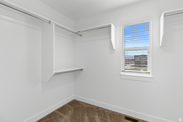 1271 West 500 South Logan, UT 84321 - Photo 18 of 26 Walk-in closet featuring white built-in shelving, chrome hanging rods, a window with horizontal blinds, a floor vent, and carpet flooring