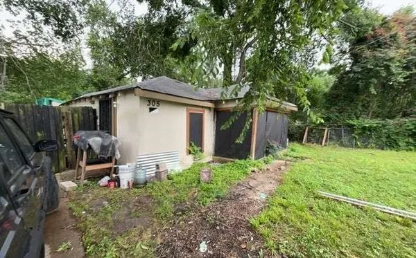 a backyard of a house with barbeque oven and trees