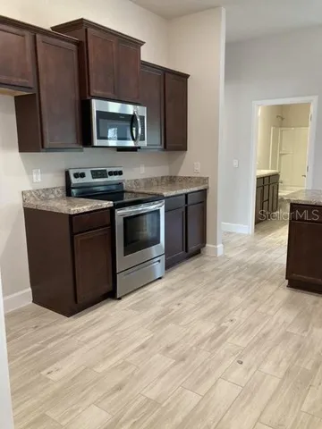 a kitchen with stainless steel appliances granite countertop a sink window and cabinets