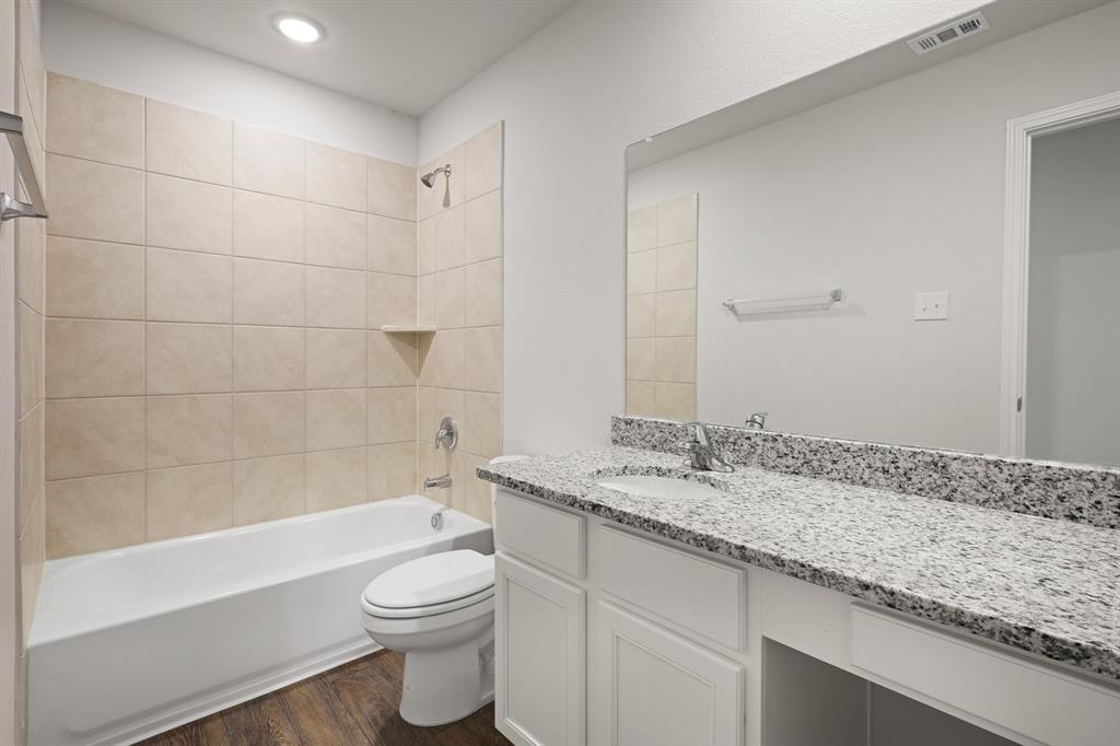 1500 Romans Road Ennis, TX 75119 - Photo 16 of 38 a bathroom with a granite countertop sink a toilet and bathtub