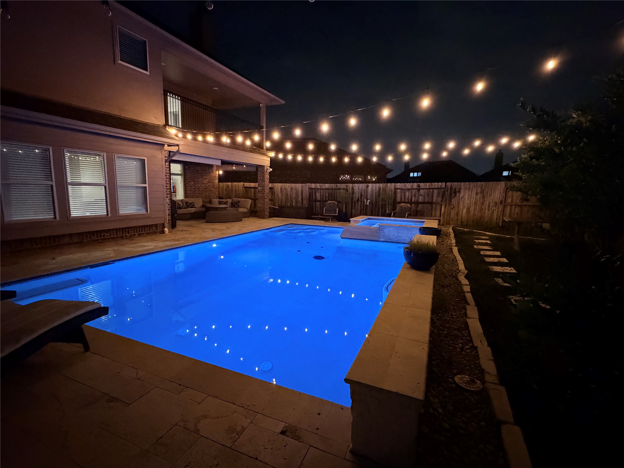 25611 Ellis Ridge Court Katy, TX 77494 - Photo 41 of 49 This inviting backyard features a beautifully lit pool surrounded by cozy seating areas and string lights, creating a perfect ambiance for evening relaxation and entertainment.