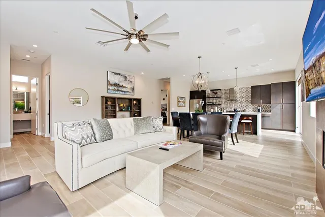 a living room with furniture kitchen view and a chandelier
