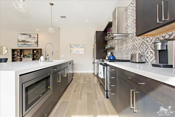 a kitchen with stainless steel appliances granite countertop a sink a stove and a wooden floors