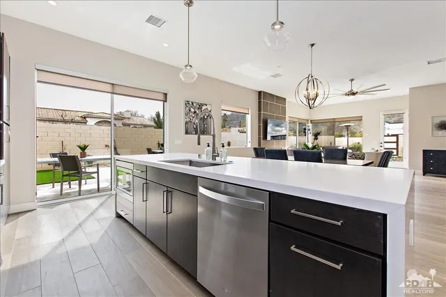 a large kitchen with a large counter space a sink appliances and cabinets