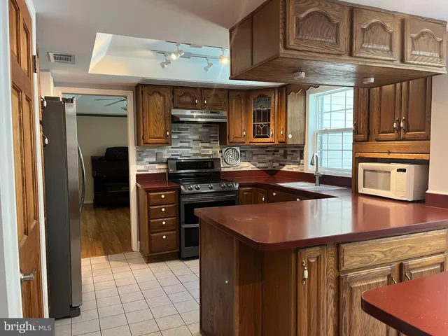 an empty room with chandelier fan and windows