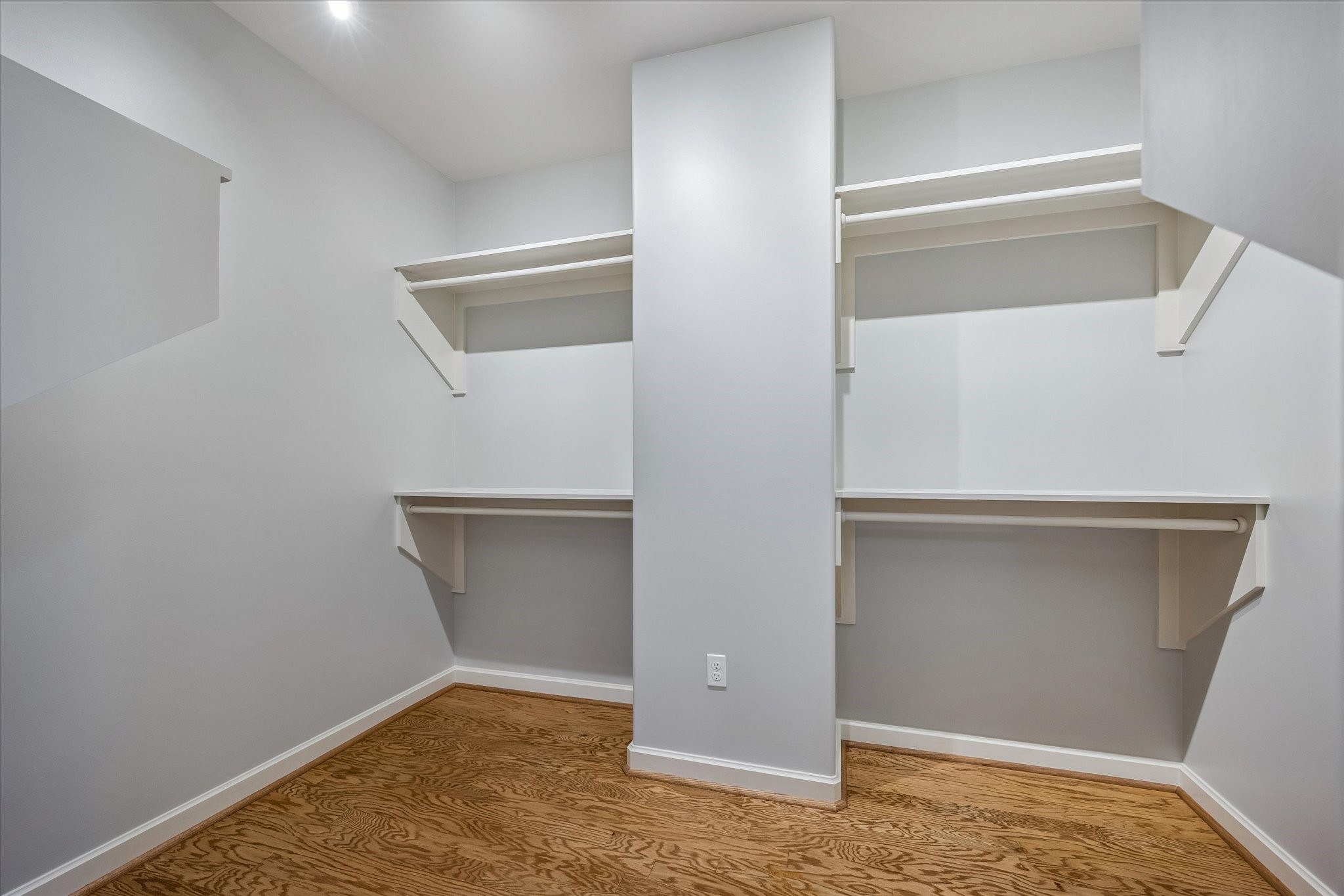 914 Main Street, Unit 910 Houston, TX 77002 - Photo 11 of 32 This is a spacious walk-in closet with wooden floors, light-colored walls, and built-in shelving for organized storage.