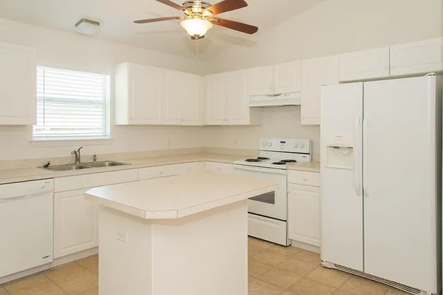 a kitchen with stainless steel appliances a sink a stove a refrigerator and cabinets