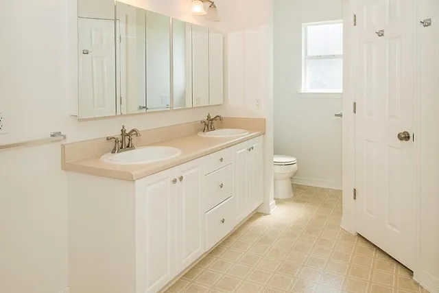 a spacious bathroom with 2 sink toilet and a mirror