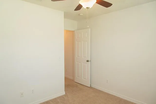 an empty room with a ceiling fan and a window