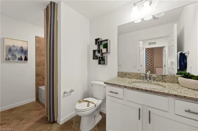 a bathroom with a granite countertop sink mirror vanity and toilet