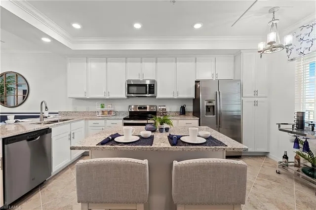 a kitchen with stainless steel appliances granite countertop a refrigerator a stove a sink dishwasher a dining table and chairs with white cabinets