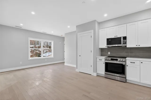 a view of a kitchen with stainless steel appliances granite countertop a stove a sink and a microwave