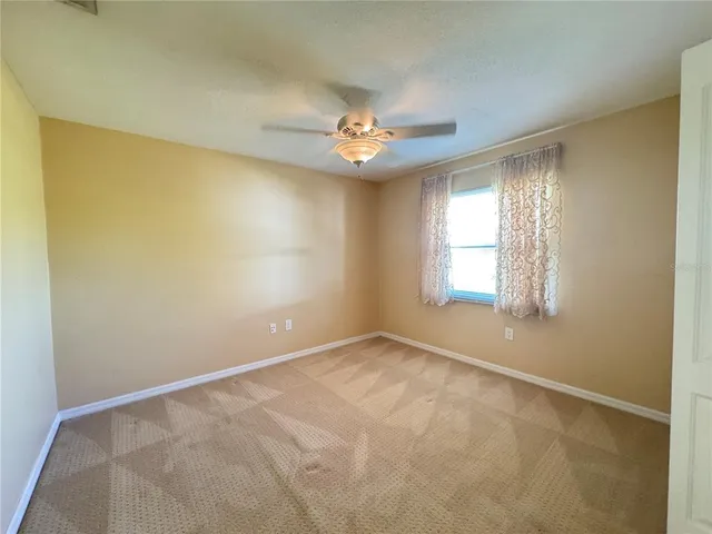 an empty room with a window and a ceiling fan