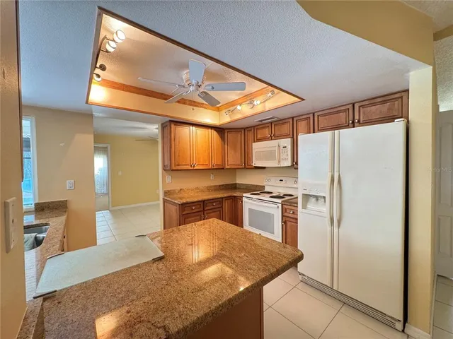 a kitchen with stainless steel appliances granite countertop a refrigerator a stove and a sink with wooden floor