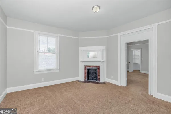 an empty room with fireplace and a window