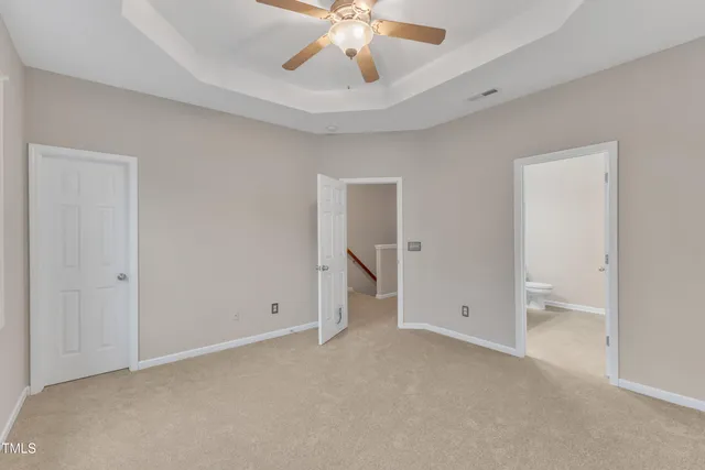 an empty room with chandelier fan and entryway