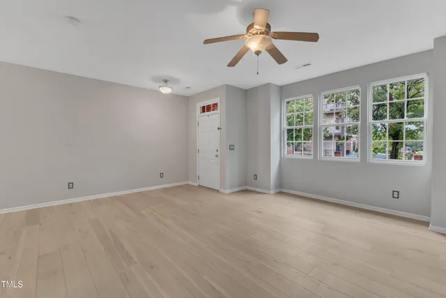 an empty room with windows and ceiling fan