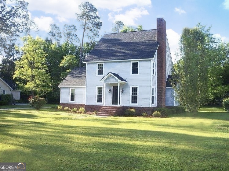 a view of a house with a big yard and large trees