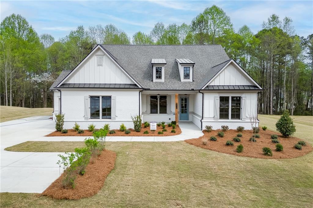 a front view of house with yard outdoor seating and trees in the background