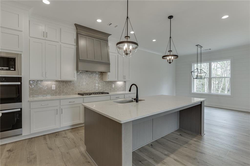 5410 Settingdown Road Cumming, GA 30041 - Photo 20 of 47 a kitchen with a sink chandelier stainless steel appliances and cabinets