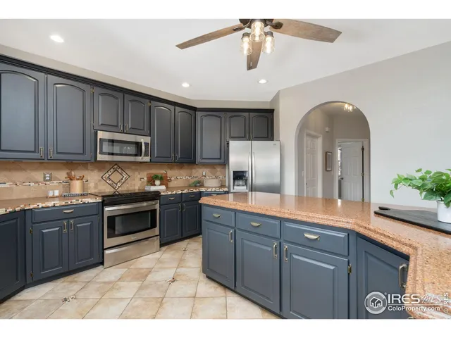 a kitchen with stainless steel appliances granite countertop a sink a stove a refrigerator cabinets and a dining table