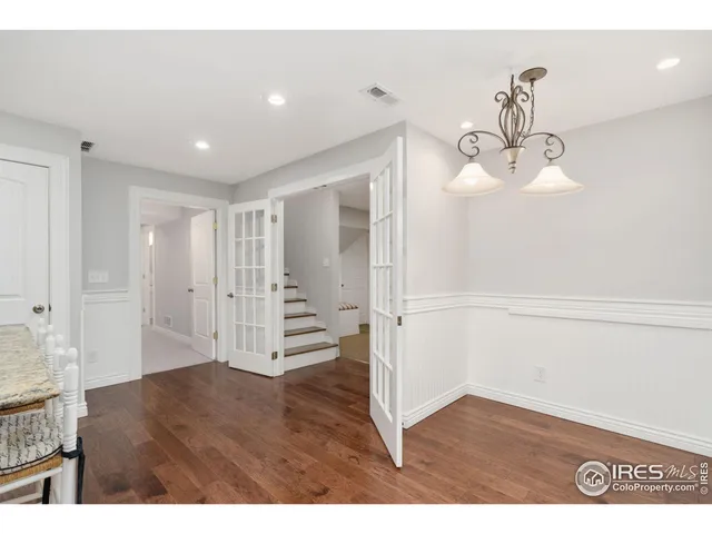 a view of an empty room with wooden floor and staircase