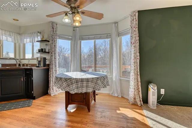a dining room with wooden floor a chandelier fan a wooden table and chairs
