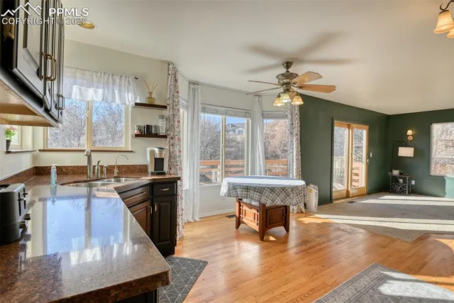 a living room with stainless steel appliances granite countertop furniture wooden floor and a kitchen view