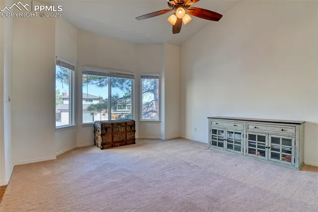 an empty room with chandelier fan and windows