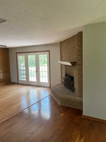 an empty room with wooden floor fireplace and windows