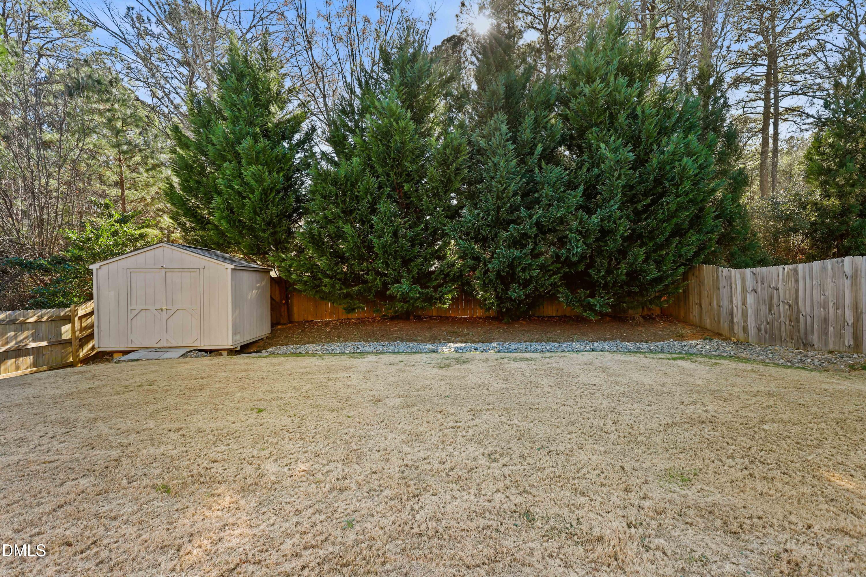 2039 Travern Drive Raleigh, NC 27603 - Photo 46 of 49 a backyard of a house with large trees and wooden fence