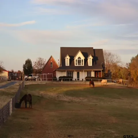 a view of a big house with a big yard and large trees