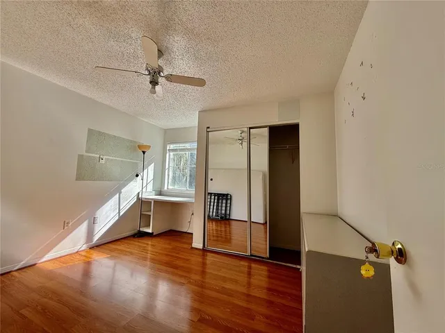 a view of a room with wooden floor and ceiling fan