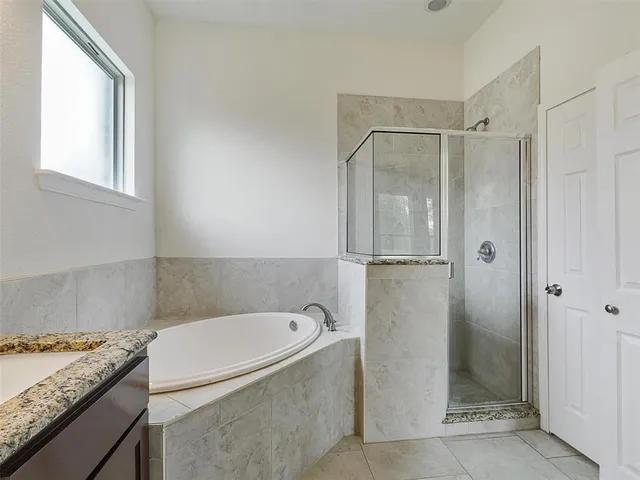 a bathroom with a granite countertop bathtub a shower and a sink