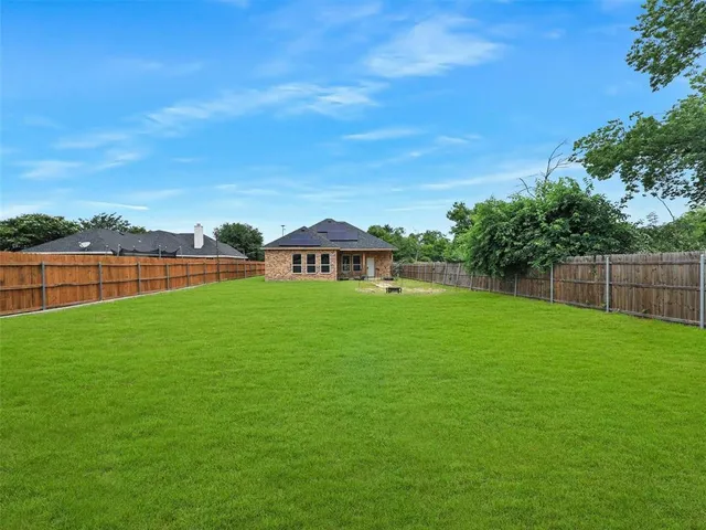 a view of a green field with house in the background