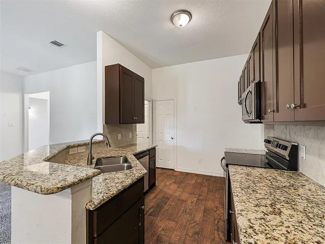 a kitchen with granite countertop kitchen island a sink stainless steel appliances and cabinets