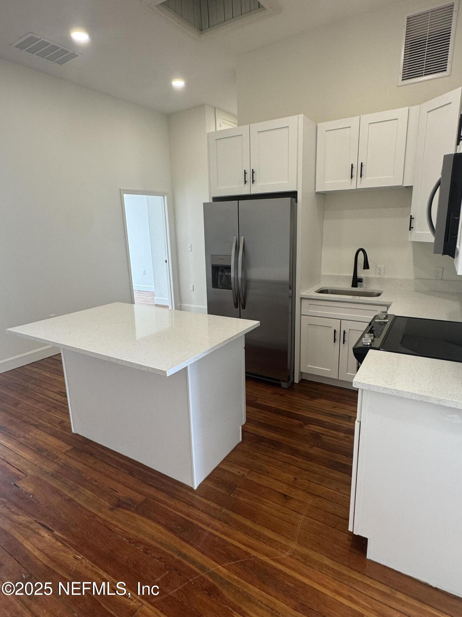 115 East Call Street Starke, FL 32091 - Photo 4 of 11 a kitchen with stainless steel appliances a stove a sink and white cabinets with wooden floor