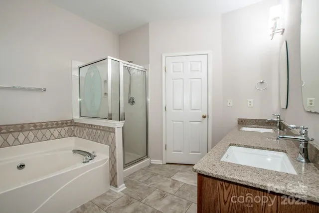 a bathroom with a granite countertop tub sink and mirror