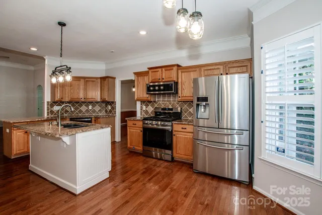 a kitchen with stainless steel appliances a refrigerator a stove a sink and a chandelier