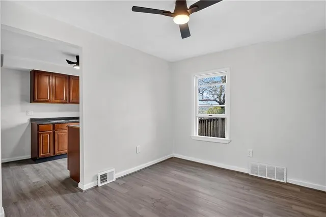 an empty room with wooden floor cabinet and windows