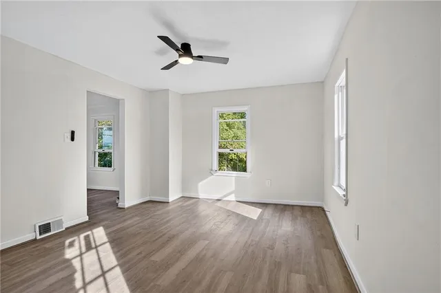 an empty room with wooden floor and windows