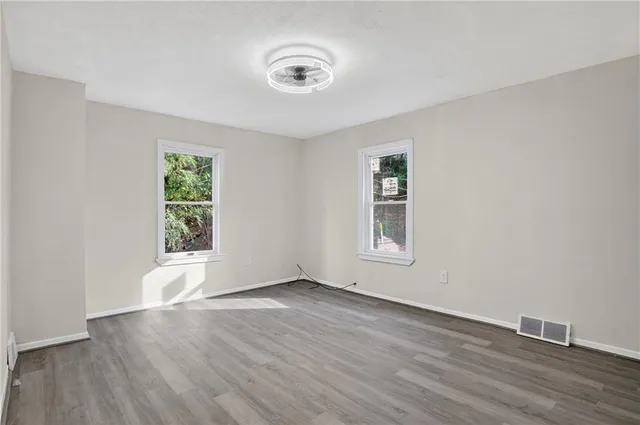 an empty room with wooden floor and windows