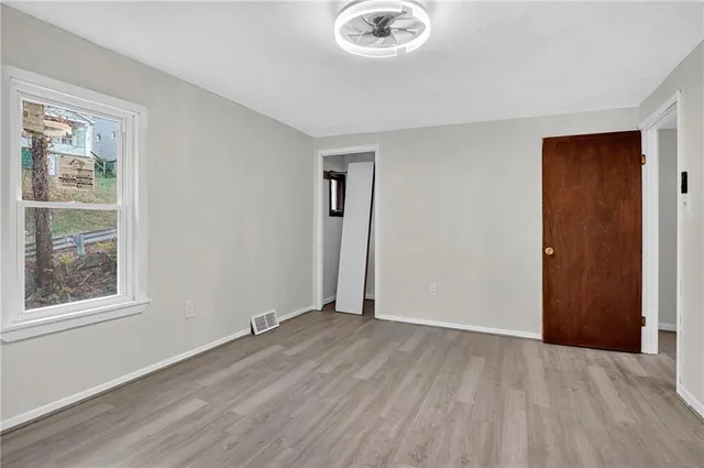 a view of an empty room with window and wooden floor