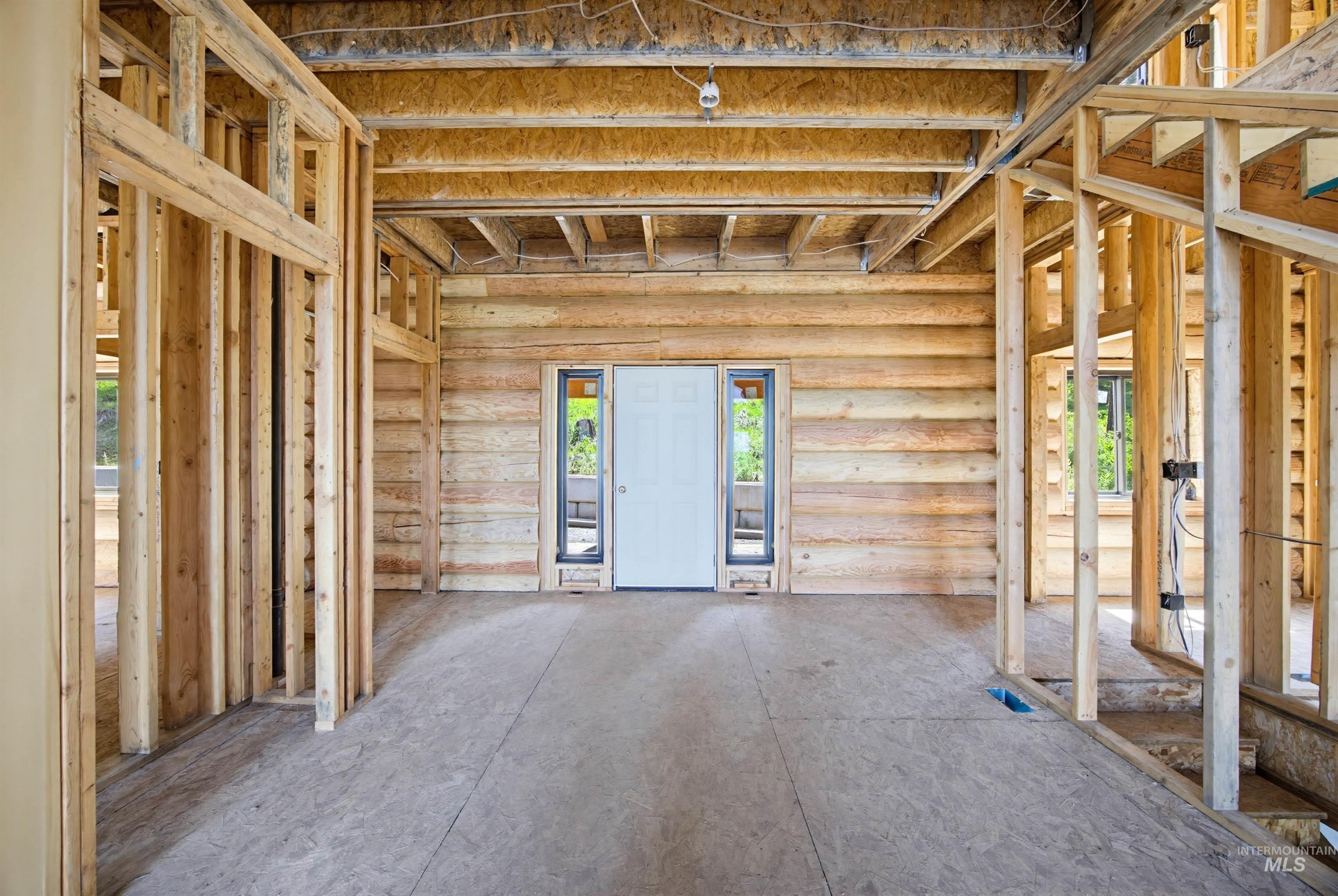 3322 Big Creek Road New Meadows, ID 83654 - Photo 47 of 50 Framed interior featuring log wall construction, exposed ceiling joists, plywood subflooring, and a white entry door with sidelight windows