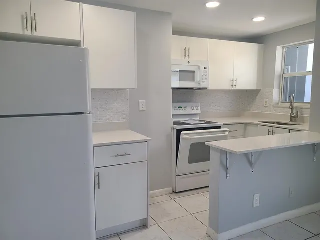 a kitchen with white cabinets and white appliances