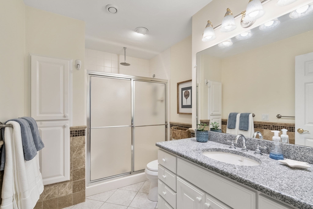 64 Gold Leaf Lane, Unit 64 Mashpee, MA 02649 - Photo 20 of 38 a bathroom with a granite countertop sink a mirror and shower