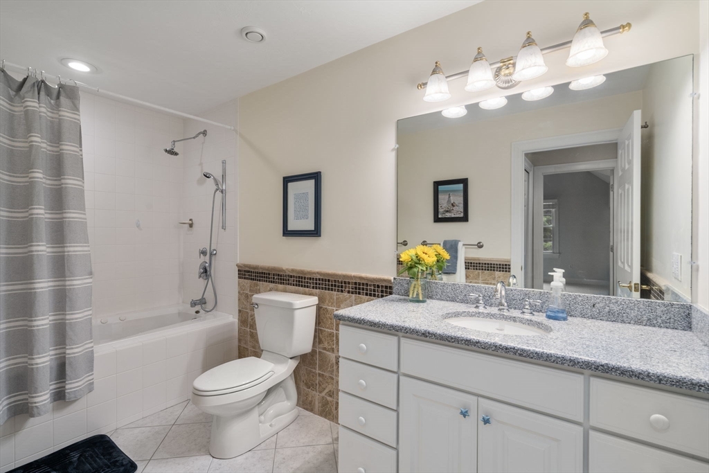 64 Gold Leaf Lane, Unit 64 Mashpee, MA 02649 - Photo 24 of 38 a bathroom with a granite countertop toilet a sink a bathtub a mirror and shower