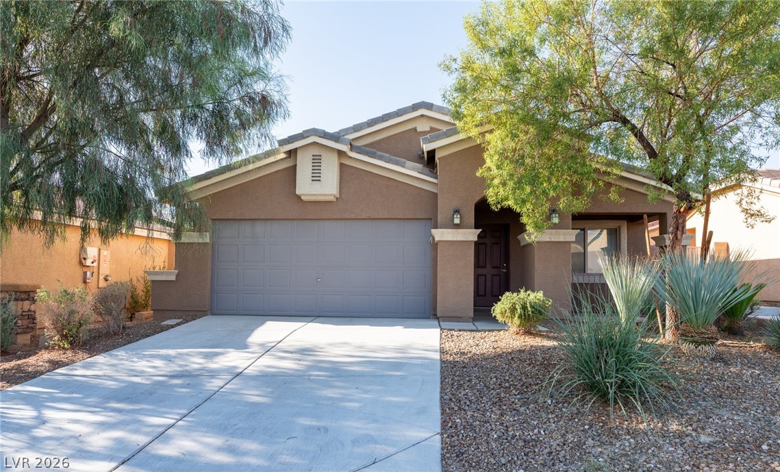 8079 Buffalo Ranch Avenue Las Vegas, NV 89147 - Photo 1 of 29 Mature trees frame the stucco exterior and concrete driveway of this inviting home.