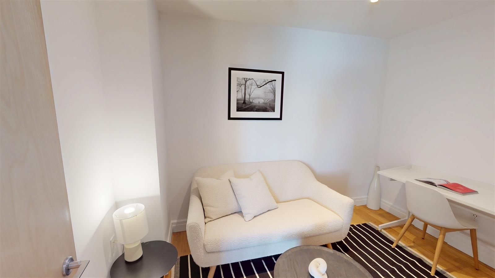 550 West 54th Street, Unit 952 Manhattan, NY 10019 - Photo 4 of 27 a living room with furniture and a lamp